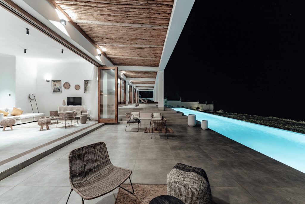 Elegant interior and exterior patio design showcasing minimalist luxury and a swimming pool under night sky.